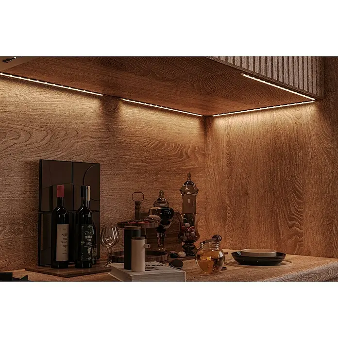 Tween Light Lichtleiste 4er Set - Länge: 160 cm, Lichtfarbe: Mehrfarbig, 0,15 W, Anzahl Leuchtmittel: 60 Stk. - Gemütliche Nischenbeleuchtung mit LED-Streifen über einer Anrichte mit Weinflaschen und dekorativen Gläsern. Warmes, indirektes Licht für Ambiente.