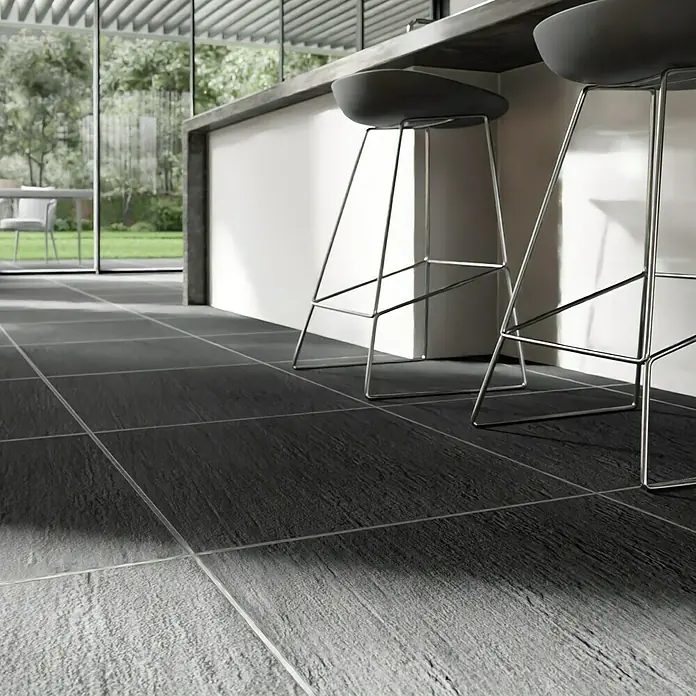 Terrassenfliese Slate Black - 60 x 60 x 2 cm, Schwarz, Matt - Blick auf moderne, graue Fliesen in einem stilvollen Küchenbereich mit Barhockern, die eine elegante Atmosphäre schaffen.