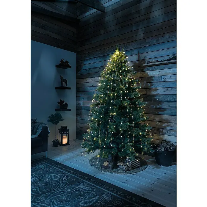 Konstsmide LED-Lichterkette Baummantel - Innen, Lichtfarbe: Bernstein, Anzahl Leuchtmittel: 240 Stk., Netzbetrieben - Festlicher Weihnachtsbaum mit funkelnden Lichterketten in gemütlicher Atmosphäre. Die warmen Lichter betonen die festliche Stimmung im Raum.