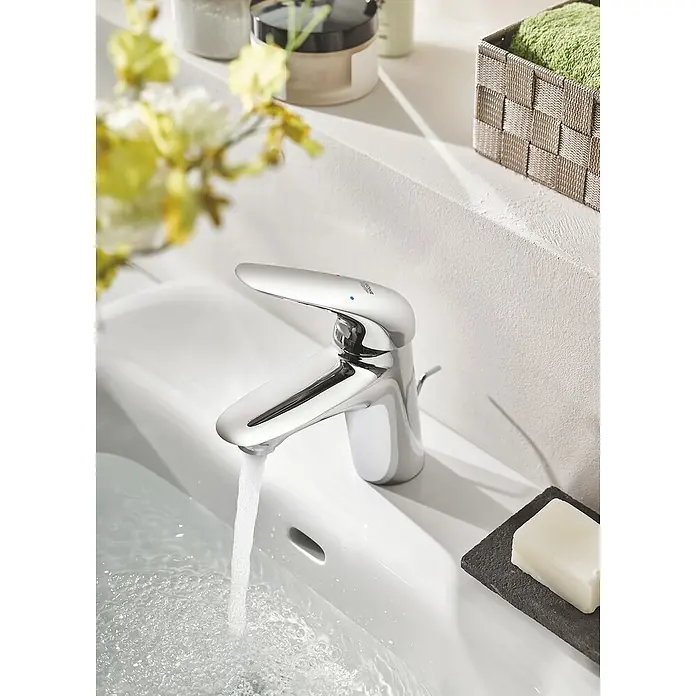 Grohe Eurostyle Solid Waschtischarmatur S-Size - Chrom, Glänzend, Mit Zugstange - Nahaufnahme eines Grohe Wasserhahns über einem Waschbecken mit fließendem Wasser. Ideal für Bad- oder Küchenarmaturen Werbung.