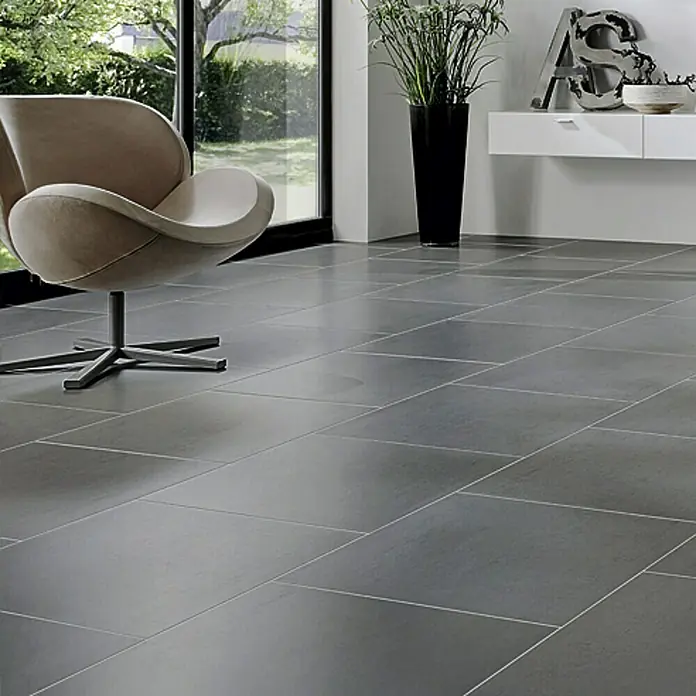 Feinsteinzeugfliese Cemento - 61,5 x 61,5 cm, Grau, Matt - Elegantes Interieur mit großformatigen, grauen Fliesen, die eine moderne und stilvolle Atmosphäre schaffen, ergänzt durch einen bequemen Sessel und Zimmerpflanzen.