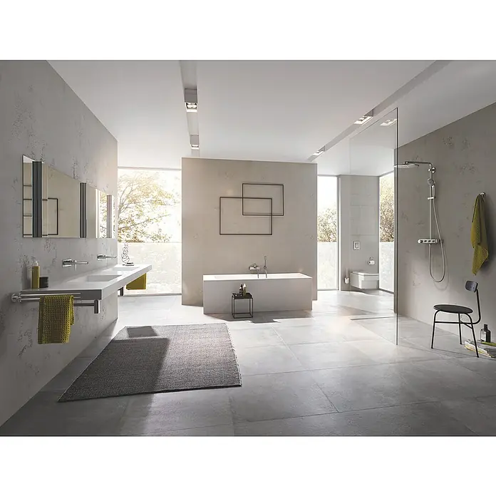 Grohe Lineare Badewannenarmatur - Ausladung Armatur: 184 mm, Supersteel, Matt - Ein modernes Badezimmer mit grauem Teppich, Badewanne, Dusche und Waschtisch. Das Design ist minimalistisch und elegant.
