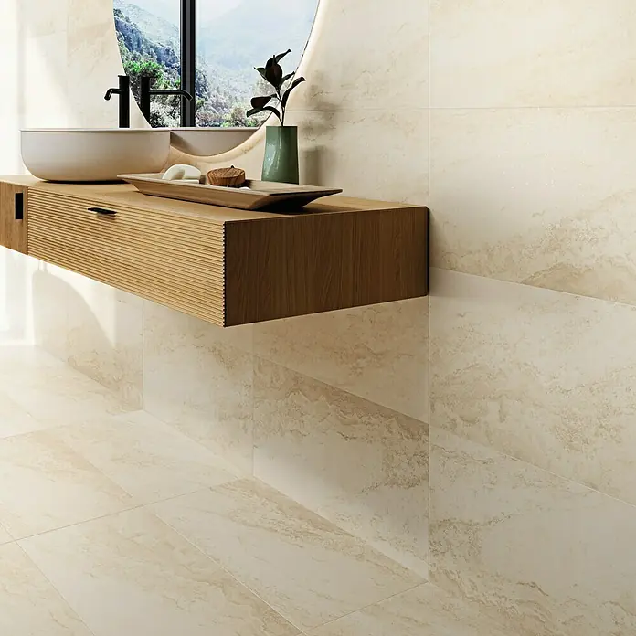 Feinsteinzeugfliese Royal White - 32,6 x 65,2 cm, Weiß, Matt - Ein Badezimmer mit beigen Fliesen, einem hellen Holzwaschtisch und einem runden Spiegel. Der Waschtisch ist mit einem Waschbecken und Accessoires dekoriert.