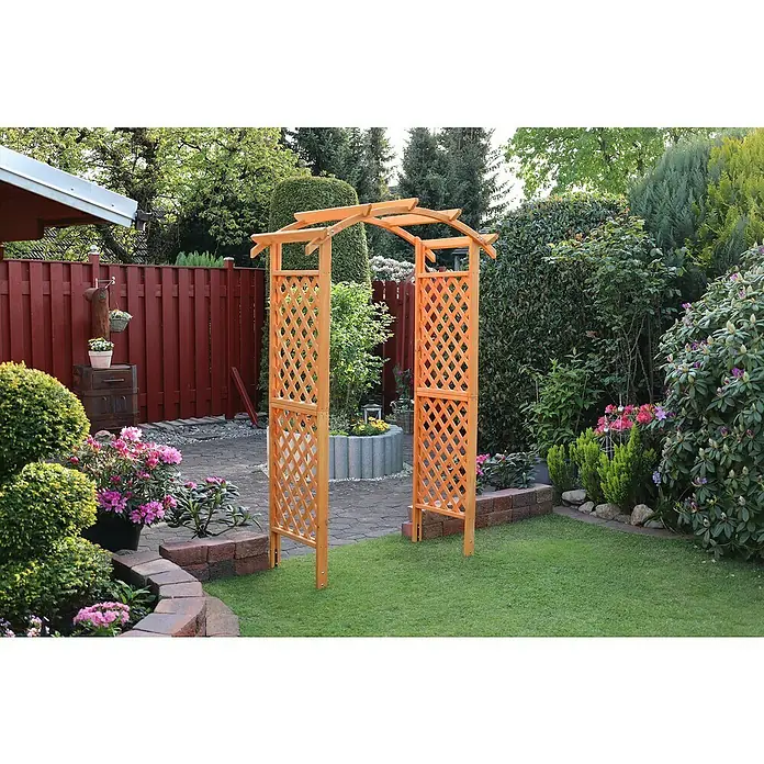 Promadino Rosenbogen Diana132 x 70 x 209 cm, Honig, Holz - Ein hölzerner Rosenbogen mit Gitterwerk steht im Garten, umgeben von üppigem Grün und bunten Blumen. Er lädt zum Verweilen ein.