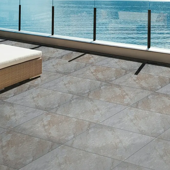 Terrassenfliese Nevada - 60 x 60 x 2 cm, Braun, Matt - Großformatige Fliesen auf einer Terrasse mit Meerblick. Die Fliesen haben ein natürliches Steinmuster.