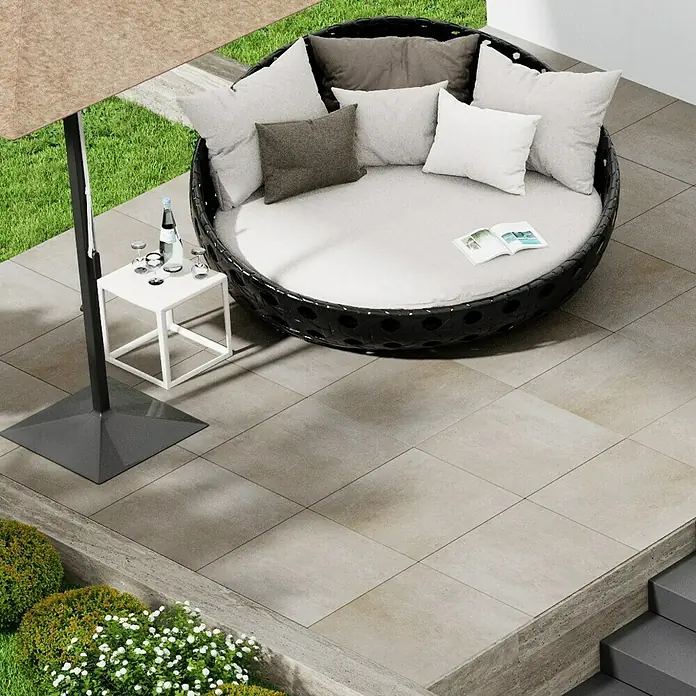 Marazzi Terrassenfliese Esterno 20T Plaster Sand - 60 x 60 x 2 cm, Sand, Matt - Gartenmöbel-Szene mit rundem Liegesessel, Beistelltisch und Sonnenschirm, die eine entspannende Atmosphäre im Freien vermittelt.