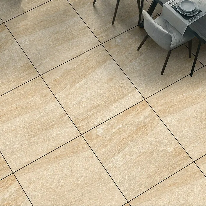 Terrassenfliese Lava Stone 2.0 - 60 x 60 x 2 cm, Beige, Matt - Beige Bodenfliesen mit dunklen Fugen auf einem Boden, der einen Teil eines Tisches und Stuhls zeigt. Ideal für moderne Interieurs.
