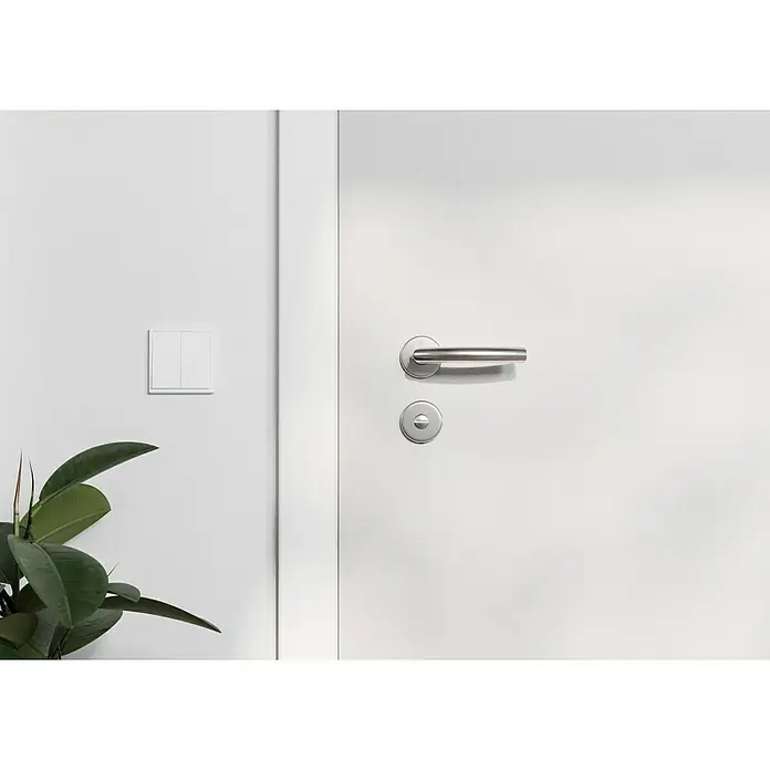 Hoppe Zimmertürgarnitur WC Narvik - Stärke Tür: 38 mm - 45 mm, Edelstahl, Schlitzkopf/Olive - Nahaufnahme einer modernen, weißen Innentür mit silbernem Türgriff und Lichtschalter, ergänzt durch eine grüne Zimmerpflanze.