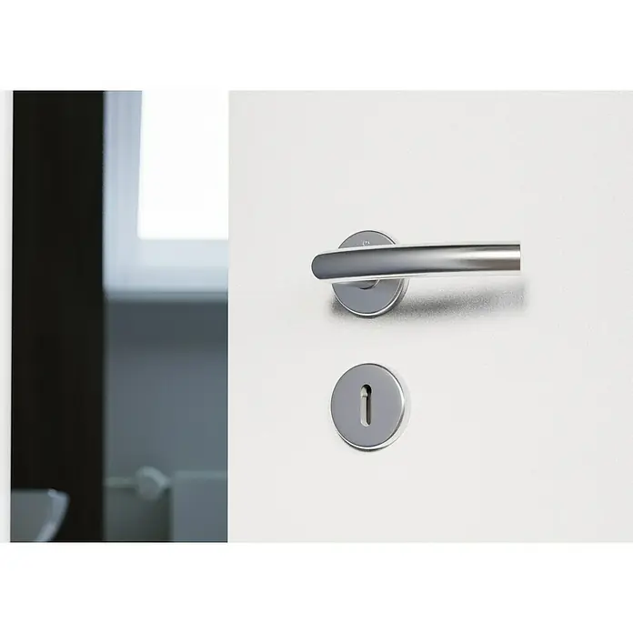 Hoppe Zimmertürgarnitur Narvik - Stärke Tür: 38 mm - 45 mm, Edelstahl, Buntbart - Nahaufnahme einer weißen Tür mit einem modernen silbernen Türgriff und Schlüsselloch, die ein elegantes und minimalistisches Design zeigt.