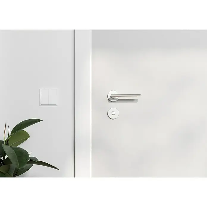 Hoppe Zimmertürgarnitur WC Stockholm - Stärke Tür: 37 mm - 42 mm, Aluminium, Schlitzkopf/Olive - Nahaufnahme einer modernen, weißen Innentür mit einem eleganten, silbernen Türgriff und einem Lichtschalter an der Wand daneben.