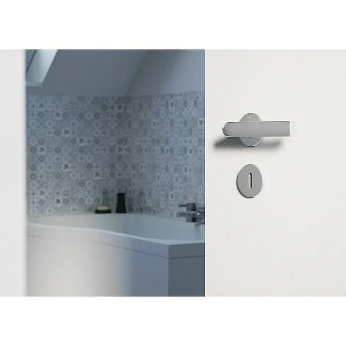 Hoppe Zimmertürgarnitur Hamburg - Stärke Tür: 42 mm - 37 mm, Aluminium, Silber, Buntbart - Ein moderner Türgriff aus gebürstetem Metall an einer weißen Tür, der ein Badezimmer mit Badewanne und gemusterten Fliesen teilweise verdeckt.