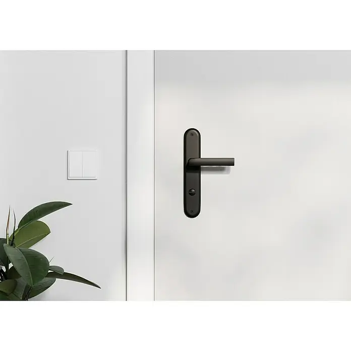 Hoppe Zimmertürgarnitur WC Hamburg - Stärke Tür: 42 mm - 37 mm, Aluminium, Schlitzkopf/Olive - Nahaufnahme einer modernen Tür mit einem eleganten, schwarzen Türgriff, der das minimalistische Design des Raumes betont.