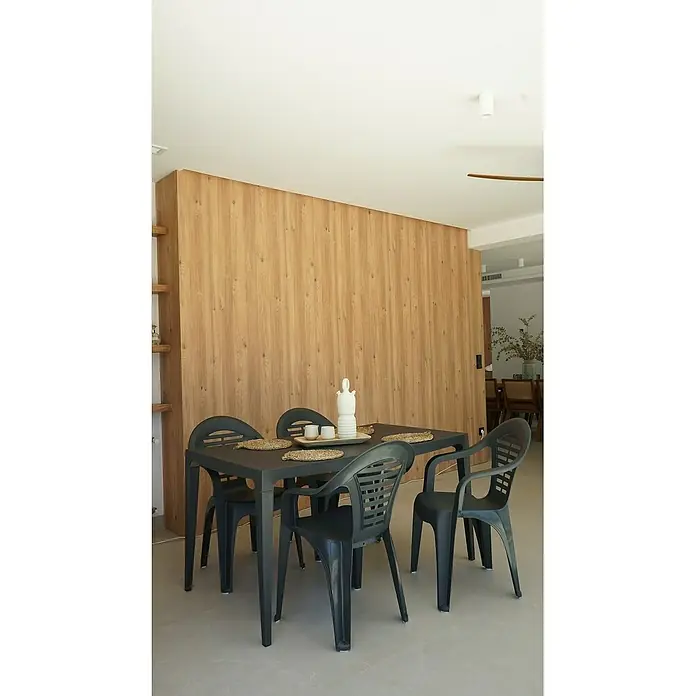 Silla de jardín Menorca - 58,5 x 54 x 79 cm, Antracita, Polipropileno, Apilable - Mesa de comedor negra con cuatro sillas y manteles individuales decorativos, complementada con un elegante jarrón blanco y tazas de cerámica, frente a una pared de madera.