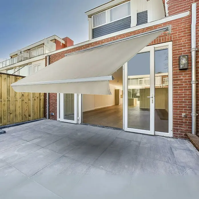 Toldo de brazos extensibles Living - Blanco, Ancho: 3 m, Caída: 2 m - Un toldo retráctil proporciona sombra en un patio, ofreciendo un espacio exterior cómodo.
