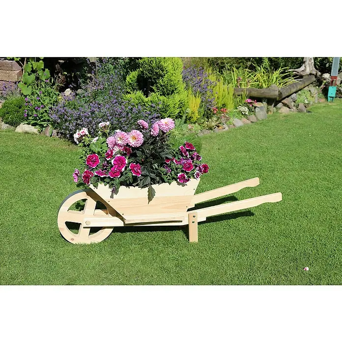 Promadino Pflanzkasten Pflanzkarre Spreewald - Außenmaß (L x B x H): 113 x 32 x 40 cm, Holz, Natur - Hölzerne Schubkarre mit rosa und violetten Blumen darauf, die auf einer Rasenfläche im Garten steht.