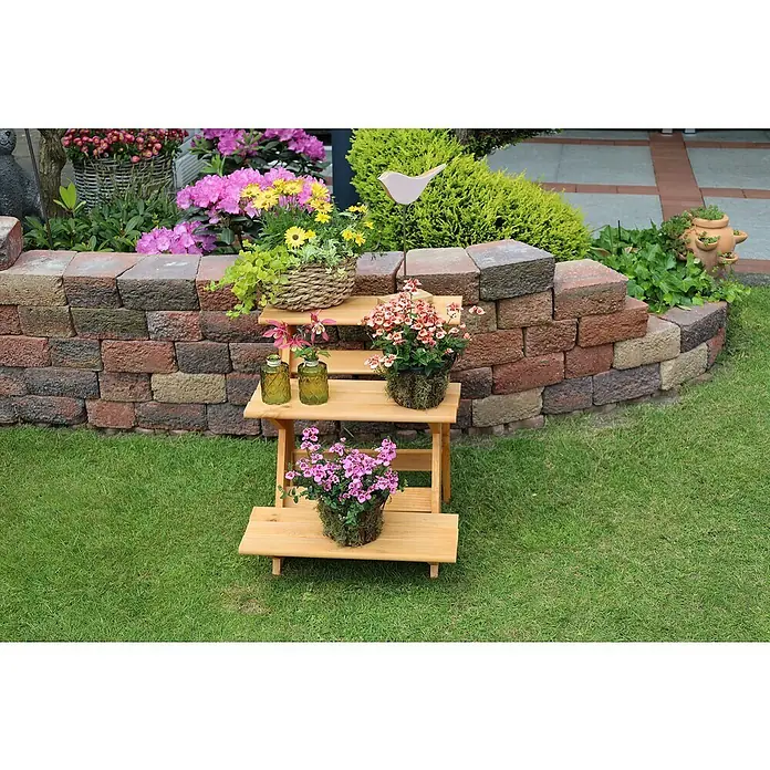 Promadino Blumentreppe - 60 x 50 x 56 cm, Kiefer, Braun - Eine dreistufige Holzpflanzentreppe mit bunten Blumen und Dekorationen vor einer Gartenmauer.