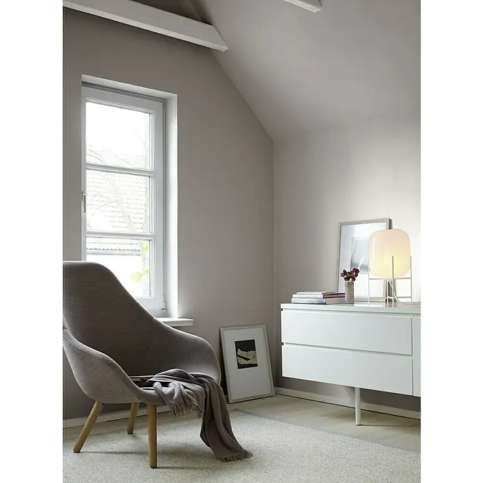 Alpina Wandfarbe Feine Farben - Poesie der Stille, Matt, 2,5 l, Konservierungsmittelfrei - Helle, moderne Leseecke mit Sessel, weißer Kommode und Stehlampe. Das Zimmer hat eine gemütliche Atmosphäre mit einem Teppich und einem Fenster für Tageslicht.