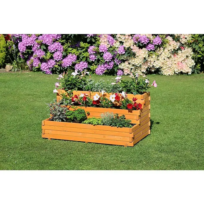 Promadino Pflanzkasten Volterra - Braun, Holz - Ein dreistufiger Pflanzkasten aus Holz, bepflanzt mit Blumen und Kräutern, steht auf einem grünen Rasen vor einem Hintergrund aus blühenden Büschen.