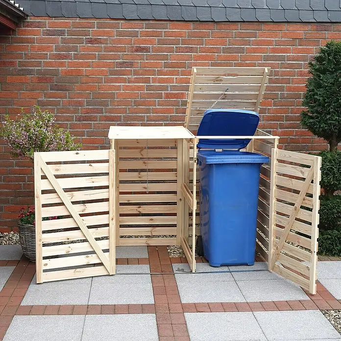 Promadino Mülltonnenbox Variov -  - Eine hölzerne Mülltonnenbox mit geöffnetem Deckel und Türen steht im Freien vor einer Backsteinmauer.