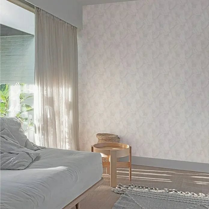 Papel pintado Pluma plata - Plata, 10 x 0,53 m - Interior de dormitorio con un sofá cama blanco, una mesa auxiliar y papel tapiz con textura, creando un ambiente tranquilo y acogedor.