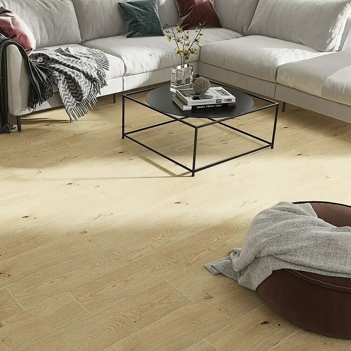 Harmonie by Palazzo Feinsteinzeugfliese - 20 x 120 cm, Creme, Matt - Nahaufnahme von hellen Holzdielen, die eine moderne Wohnzimmereinrichtung mit Couch und Couchtisch ergänzen.