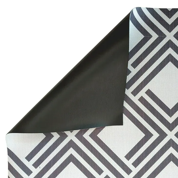 Alfombra de vinilo Living geométrica - Negro, 90 x 60 cm - Primer plano de un mantel con un estampado geométrico y una esquina levantada que revela un reverso oscuro.