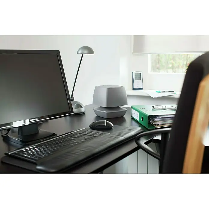 UHU Luftentfeuchter Ambiance - 450 g, Anthrazit - Büroarbeitsplatz mit einem grauen tragbaren Luftreiniger auf einem Schreibtisch mit Computer, Tastatur und Schreibtischlampe.