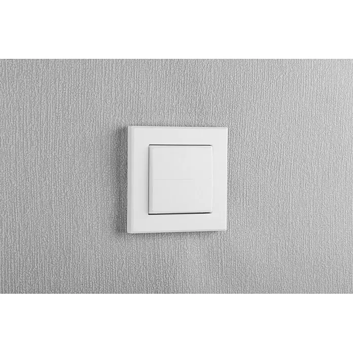 Homematic IP Taster Wippe HmIP-BRU - Ohne Pfeile, Weiß, 16 x 86 x 86 mm - Ein quadratischer, weißer Lichtschalter an einer strukturierten, grauen Wand. Das elegante Design des Schalters fügt sich nahtlos in die Wand ein.