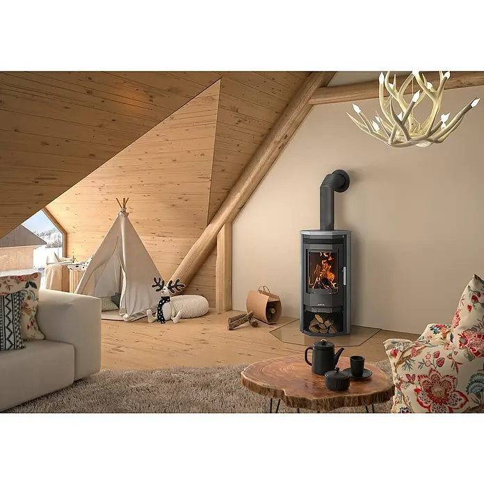 Justus Kaminofen Usedom 5 D - 5,5 kW, Raumheizvermögen: 88 m³, Material Verkleidung: Speckstein, Gussgrau - Ein gemütliches Interieur mit einem modernen Kaminofen als zentralem Element, umgeben von rustikalem Holz und sanfter Beleuchtung.