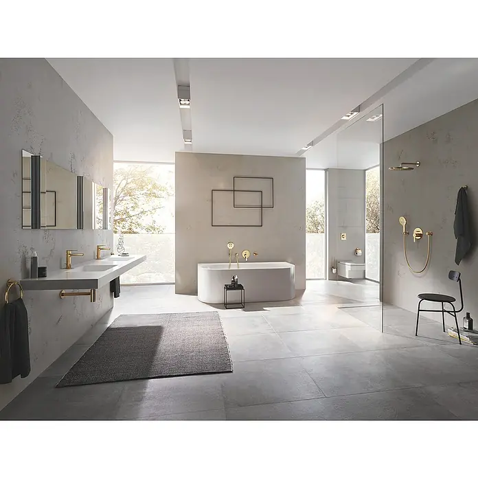 Grohe Essentials Bademantelhaken - Cool Sunrise, Glänzend - Ein modernes Badezimmer mit Doppelwaschtisch, freistehender Badewanne, Dusche und stilvollen goldenen Akzenten. Die grauen Fliesen verleihen Eleganz.