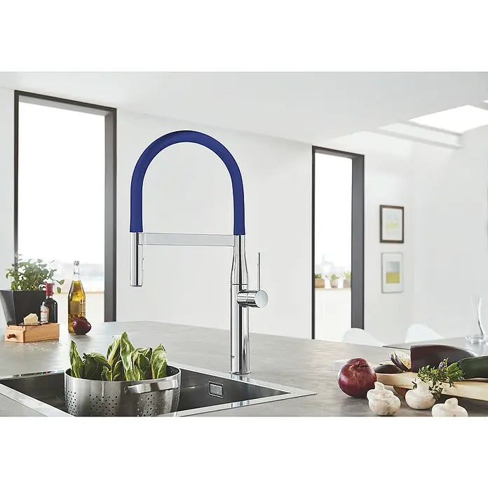 Grohe Essence Schlauchauslauf GrohFlex - Blau, Silikon - Eine moderne Küchenarmatur mit blauem Schlauchbogen und Gemüse auf einer Kücheninsel in einer hellen Küche.