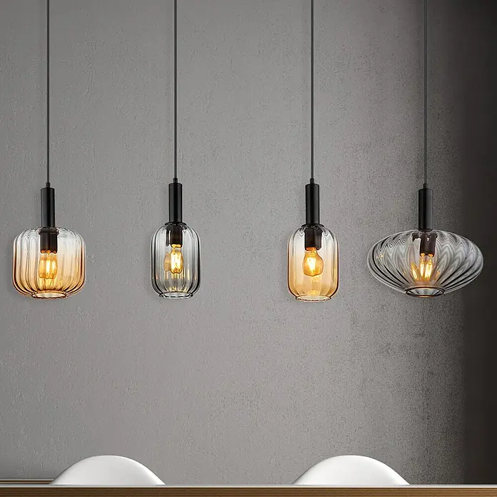 Globo Pendelleuchte Valletta - 60 W, L x B x H: 127 x 30 x 150 cm, Amber, Schwarz matt - Vier verschiedene Pendelleuchten mit dekorativen Glasschirmen und Edison-Glühbirnen, die über einer Theke hängen.
