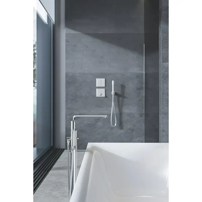 Grohe Grohtherm SmartControl UP-Ventil - Eckig, Chrom, Glänzend - Moderne Badewanne mit freistehender Armatur und grauer Wand im Hintergrund. Elegantes Design für ein entspannendes Badeerlebnis.