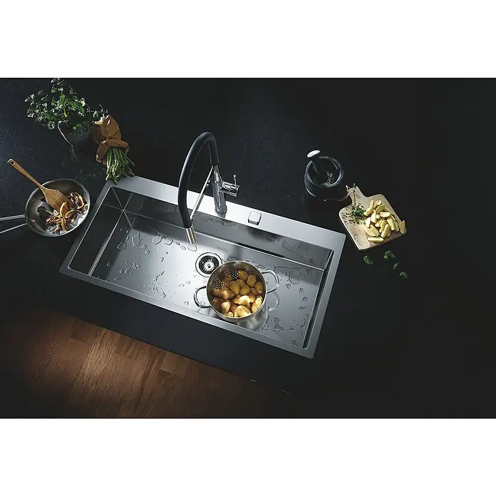 Grohe Essence Spültischarmatur - Chrom, Glänzend - Moderne Edelstahlspüle mit Armatur, Abtropffläche und einem Sieb mit Kartoffeln. Kräuter, Gewürze und ein Mörser dekorieren die Spüle.