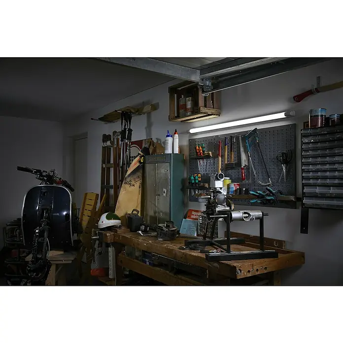 Osram LED-Lichtleiste Power Batten - L x B x H: 120 x 8,2 x 4,8 cm, Lichtfarbe: Warmweiß, 50 W, 220 V - 240 V - Werkstatt-Einblick: Eine Werkbank mit Werkzeugen, Schraubstock und einer Vespa im Hintergrund, die zum Basteln einlädt.\n
