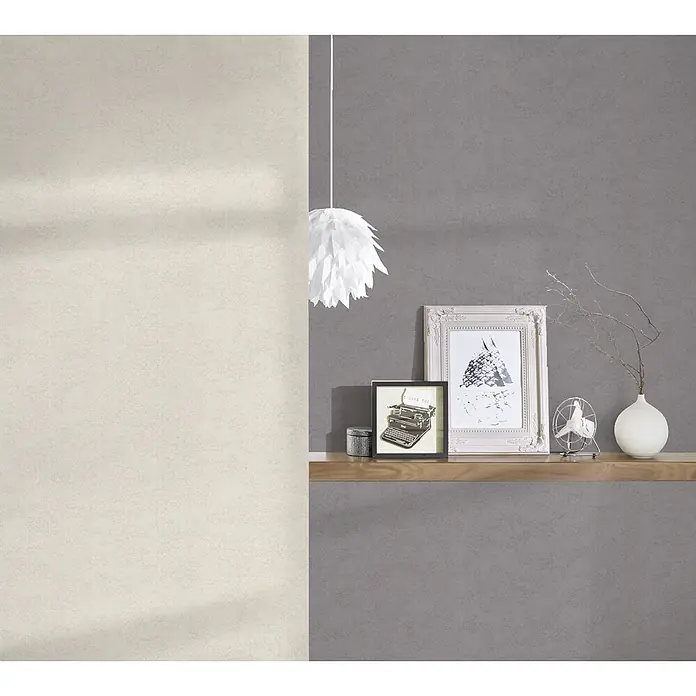 A.S. Création Vliestapete Innova - Creme, Uni, 10,05 x 0,53 m - Eine stilvolle Wanddekoration mit einer hölzernen Ablage, auf der Bilderrahmen und eine kleine Lampe stehen. Die Wand ist in zwei Farbtöne geteilt.