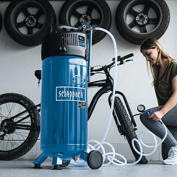 Scheppach Kompressor HC51V - 1.500 W, Max. Druck: 10 bar, 50 l, 230 V, Ansaugleistung: 220 l/min - Ein blauer Scheppach-Luftkompressor mit 50 Litern und 2,0 PS Leistung, der zum Aufpumpen eines Fahrradreifens verwendet wird.