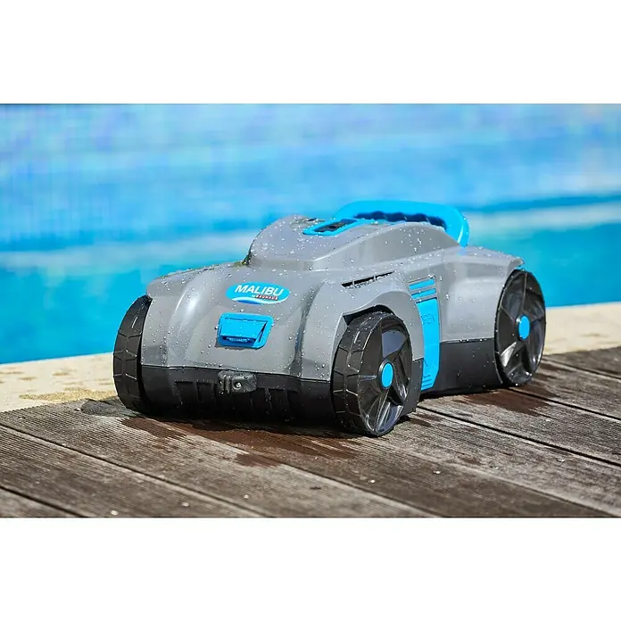 Malibu Poolroboter Akku - Akkubetrieben, Passend für: Pools mit Grundfläche bis 100 m², Filterleistung: 4.800 l/h - Malibu Poolreiniger auf Holzdeck. Der graue Poolroboter verfügt über blaue Akzente und steht vor einem Pool.