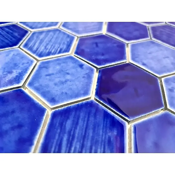 Mosaikfliese Hexagon CG SAN7 - Blau, Glänzend, L x B x S: 25,3 cm x 29,3 cm x 7 mm - Nahaufnahme von blauen Sechseck-Keramikfliesen mit unterschiedlichen Farbtönen und Texturen, die ein auffälliges Mosaikmuster bilden.