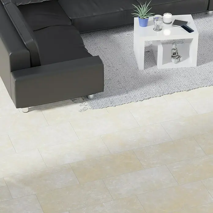 Atlas Concorde Solution Regent Feinsteinzeugfliese Ivory - 30 x 60 cm, Beige/Braun, Matt - Ein elegantes schwarzes Ledersofa mit einem modernen weißen Couchtisch, dekoriert mit einer Pflanze und Kerzen, auf einem weichen grauen Teppich.