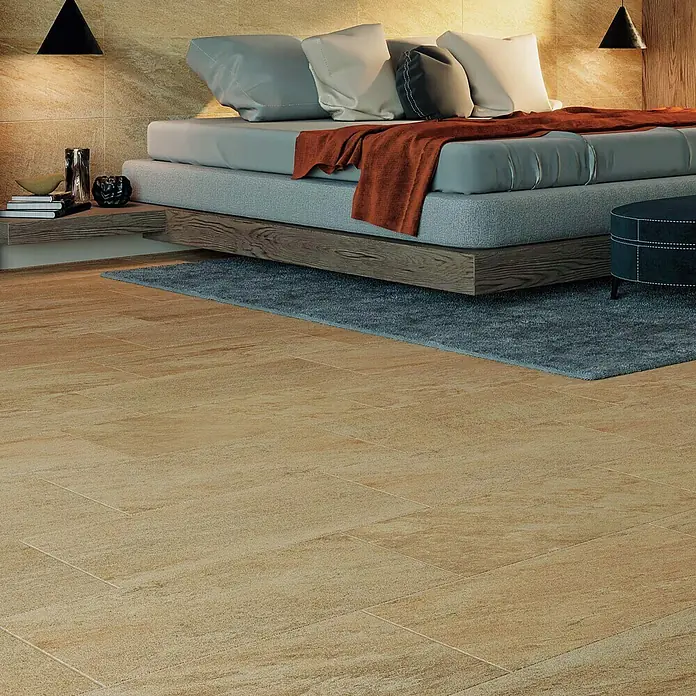 Atlas Concorde Solution Regent Feinsteinzeugfliese Gold - 30 x 60 cm, Gold, Matt - Schlafzimmer mit Holzboden und Teppich. Das Bett hat eine braune Decke und Kissen. Zwei Lampen hängen von der Decke.