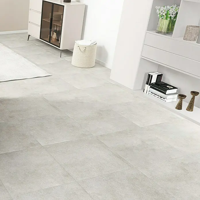 Terrassenfliese Click and Go Portland Grey60 x 60 cm, Betongrau, Matt - Diese Aufnahme zeigt einen hellen Raum mit Fliesenboden, einem weißen Teppich und stilvollen Möbeln, die ein modernes Ambiente schaffen.