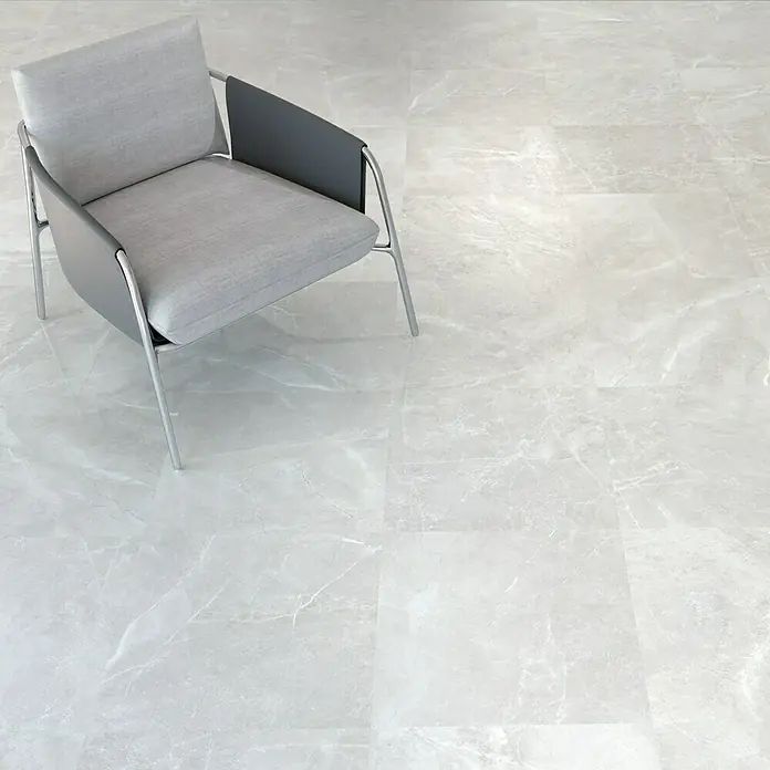 Feinsteinzeugfliese Bayona Silver - 60 x 60 cm, Grau, Glänzend - Ein moderner grauer Sessel mit minimalistischem Design steht auf einem hellen, marmorierten Fliesenboden. Elegante Akzente für jeden Raum.