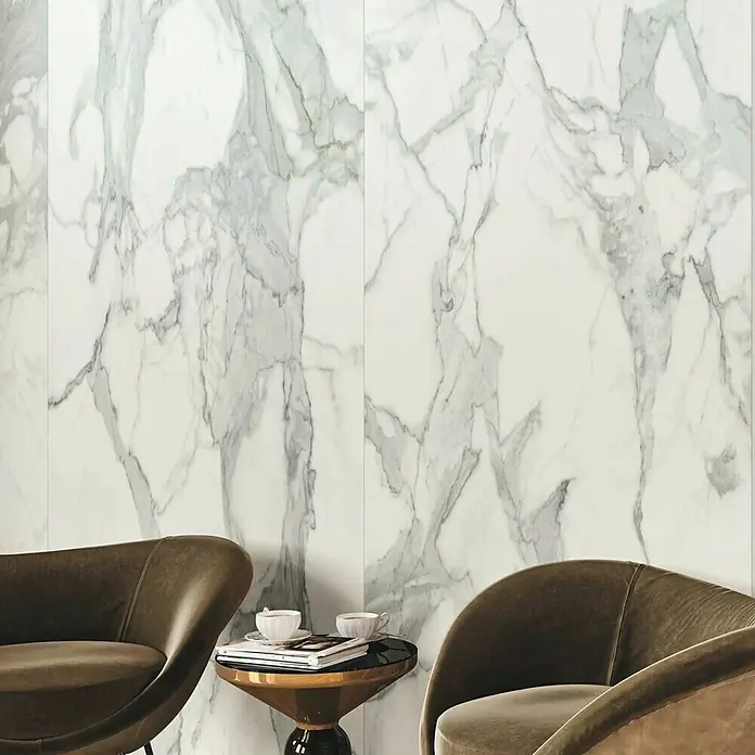 Feinsteinzeugfliese Invictus Pulido - 120 x 260 cm, Weiß/Grau, Glänzend - Elegante Marmorwand mit sanften Grautönen, ergänzt durch stilvolle Sessel und einen kleinen Tisch. Luxuriöses Ambiente für Wohnräume.
