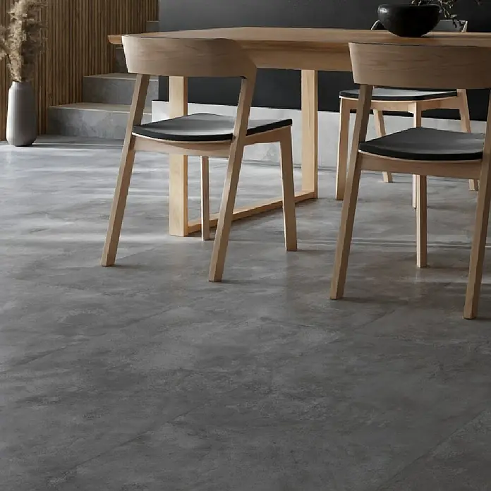 Queens Feinsteinzeugfliese - 29,8 x 59,8 cm, Grau, Matt - Nahaufnahme eines hellen Holzesstisches mit Stühlen mit schwarzen Sitzen auf einem grauen Boden, der ein modernes und minimalistisches Design zeigt.