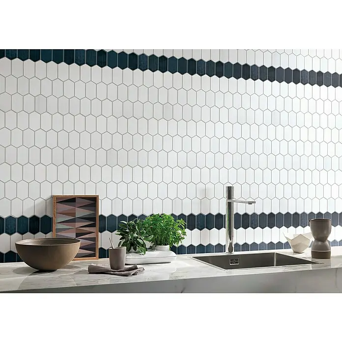 Mosaikfliese Hexagon CG CH471 - Weiß, Glänzend, 25,3 cm x 29,3 cm x 75 mm - Nahaufnahme einer Wand mit weißen und dunkelblauen, länglichen Sechseckfliesen, die ein modernes und stilvolles Muster bilden.