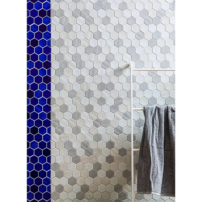 Mosaikfliese Hexagon CG SAN7 - Blau, Glänzend, L x B x S: 25,3 cm x 29,3 cm x 7 mm - Wandfliesen mit Sechseckmuster in Grau- und Blautönen, ergänzt durch eine weiße Leiter und ein graues Handtuch.
