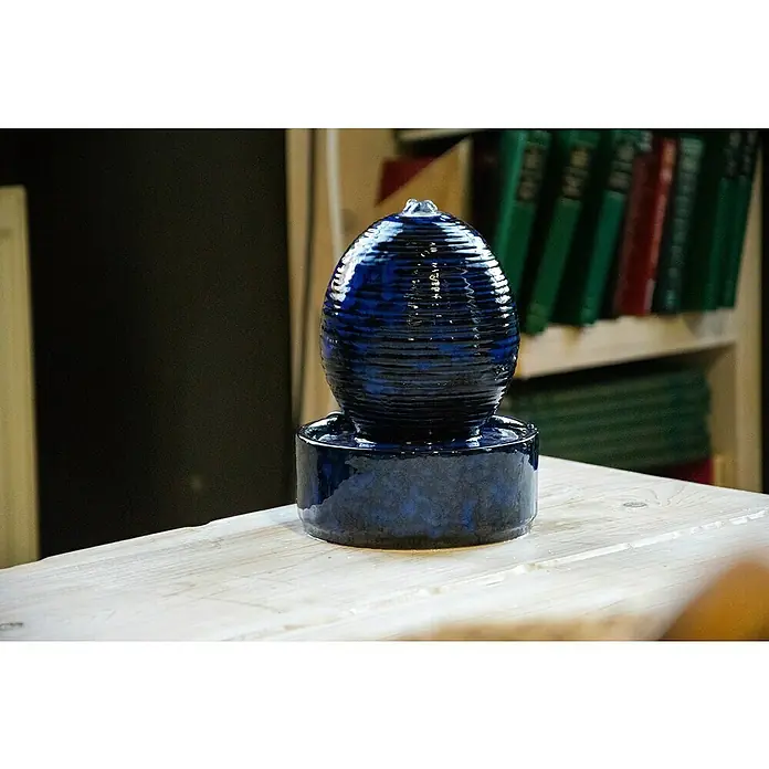 Dobar Zimmerbrunnen Kugel - L x B x H: 17 x 17 x 21 cm - Blaue Keramikbrunnen auf einem Holztisch, der eine beruhigende und elegante Note verleiht.