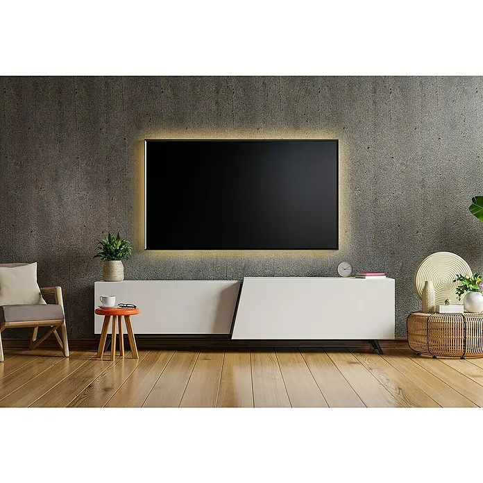 Tween Light LED-Band - Länge: 300 cm, Lichtfarbe: Warmweiß, 22 W, 275 lm - Ein modernes Wohnzimmer mit einem großen, beleuchteten Fernseher an einer Betonwand über einem weißen Lowboard. Ein Sessel und ein Hocker ergänzen das Interieur.
