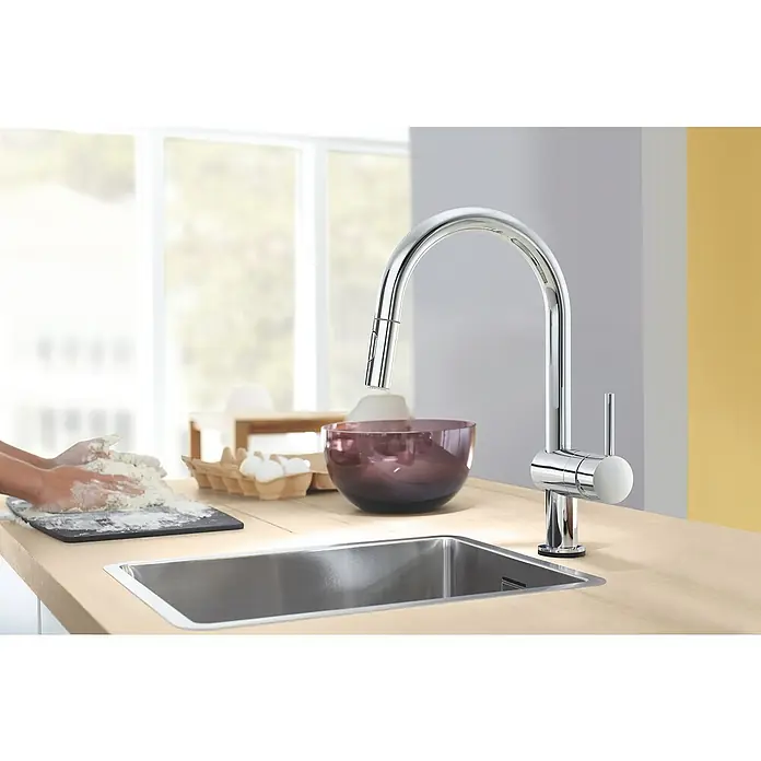 Grohe Spültischarmatur Minta Touch 2 - Chrom, Glänzend - Eine Küchenspüle mit einem modernen Chromhahn. Im Hintergrund knetet jemand Teig, was die Funktionalität der Spüle hervorhebt.